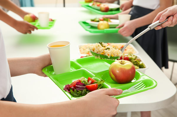 Servizi Mensa Scolastica, Mani di bambini che portano vaschette con scomparti per le diverse pietanze per il pranzo a scuola